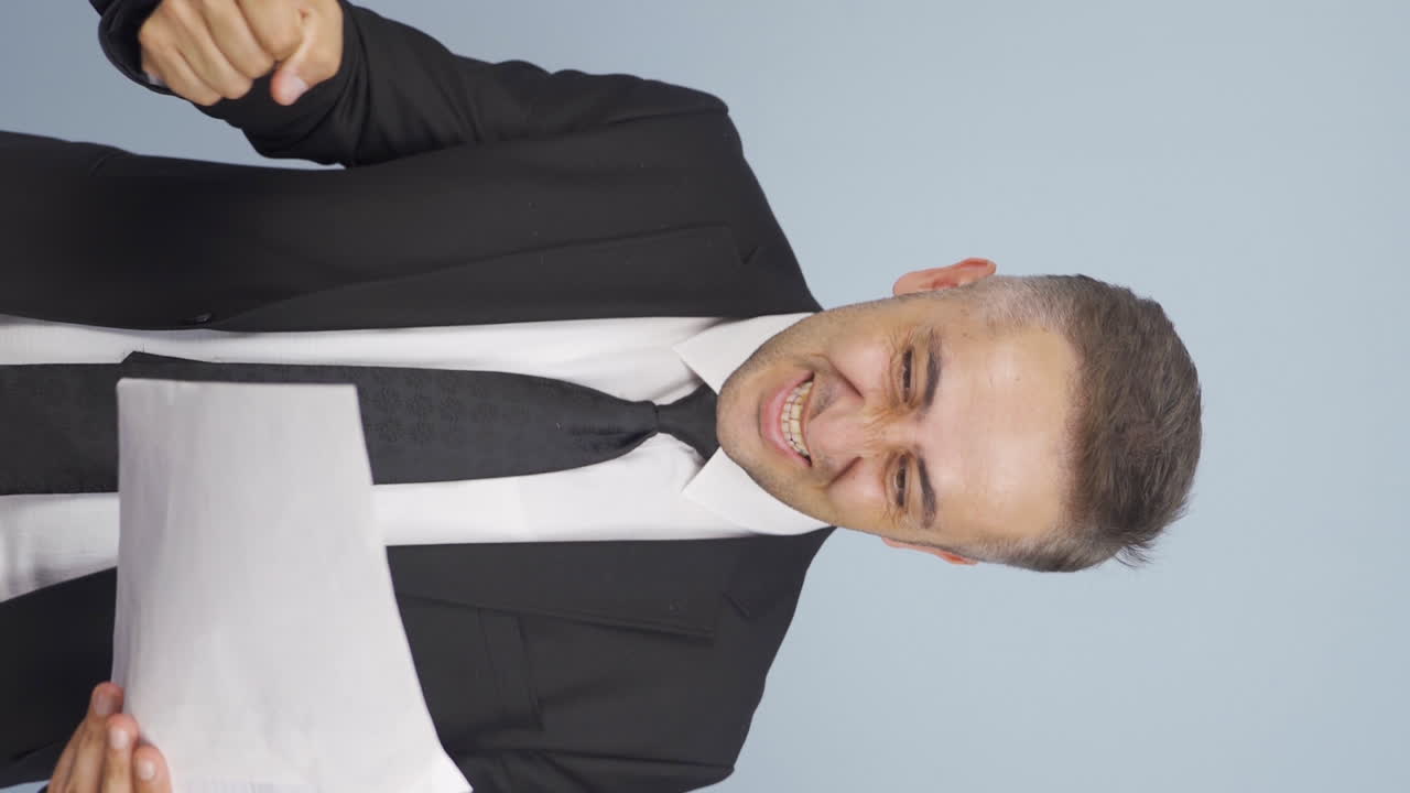 vídeo vertical del hombre de negocios mira el documento en su mano y se alegra.