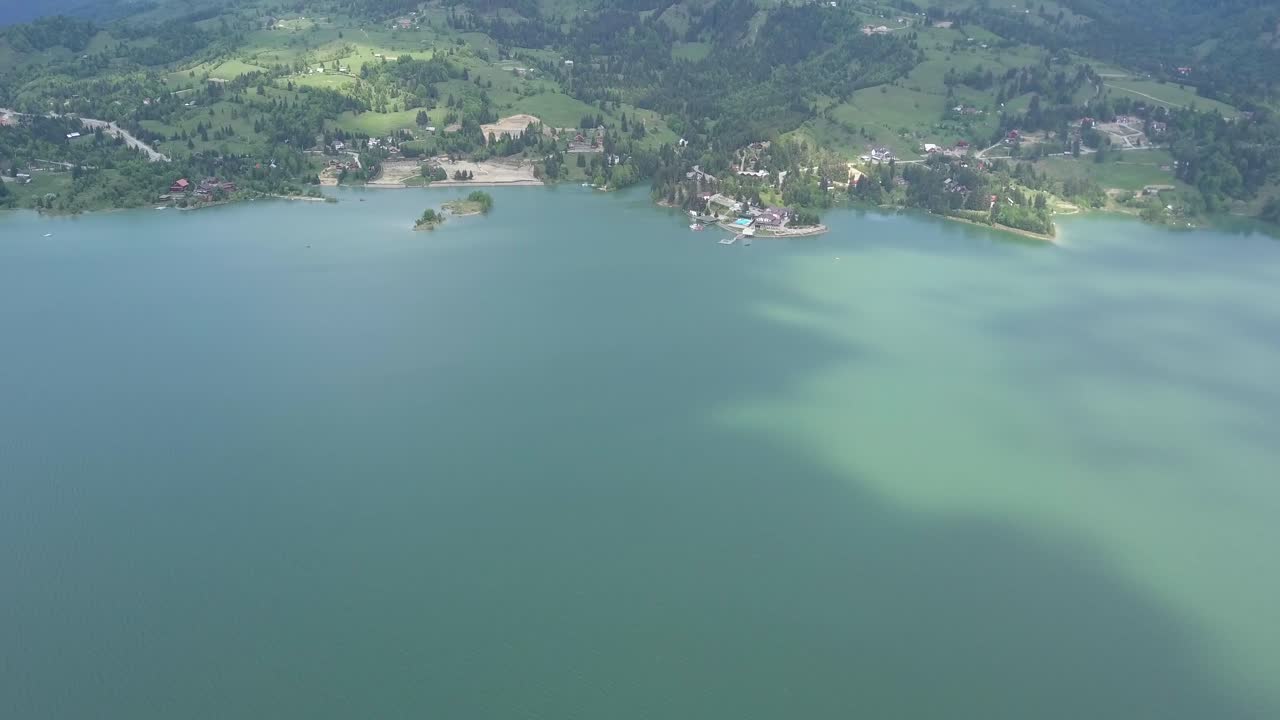 toma aérea de trípode del lago - frente del embalse junto al bosque verde y sombras en el agua de las nubes
