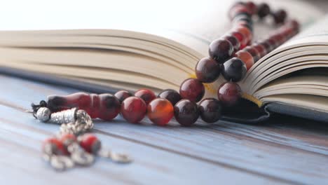 holy book quran and prayer beads on table, close up.