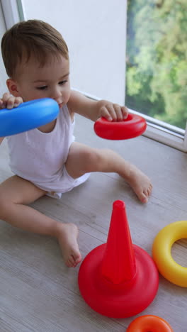 baby playing with stacking rings at the window
