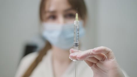 centrado en una jeringa sostenida por un profesional de la salud con una máscara, mostrando la preparación y el cuidado médicos