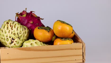 hand picking persimmon from assorted tropical fruits