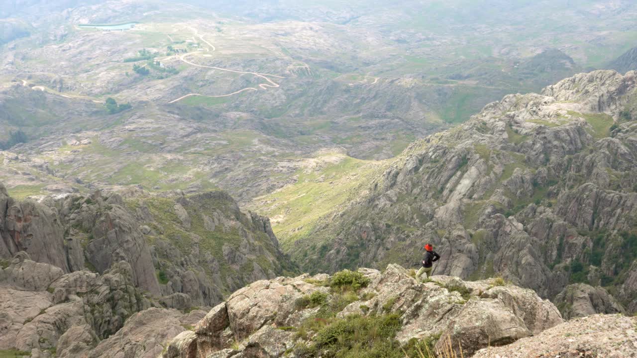 una excursionista en la cima de una impresionante cadena montañosa cerca del borde de un acantilado