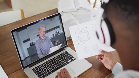 African-american-male-college-student-holding-notes-while-having-a-video-call-on-laptop-at-home