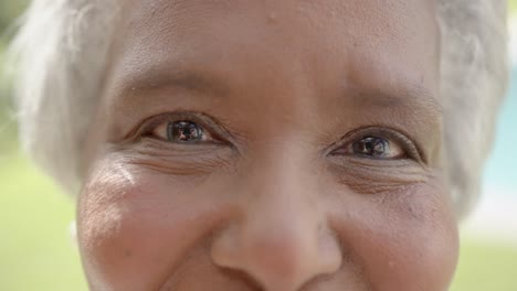 retrato de una feliz mujer biracial senior mirando a la cámara y sonriendo en el jardín, cámara lenta