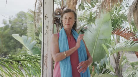 Happy-senior-caucasian-woman-enjoying-view-from-porch-of-wooden-beach-house,-in-slow-motion