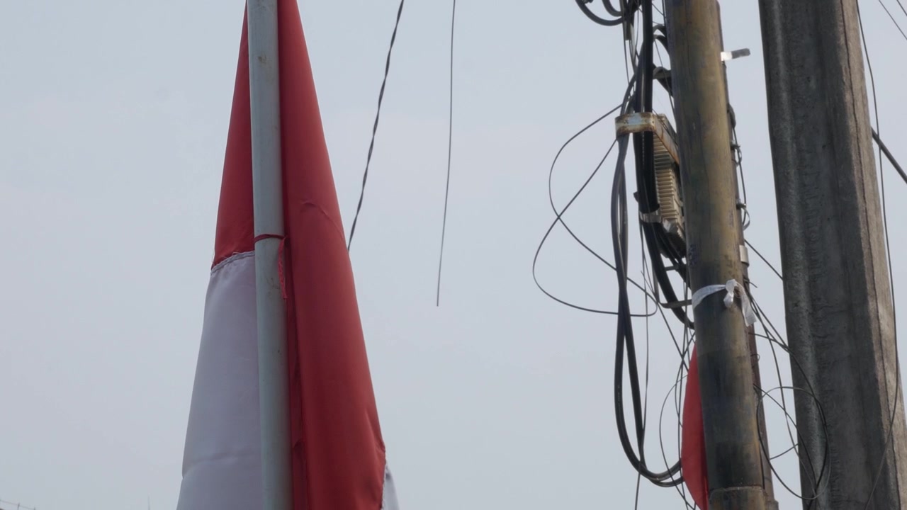 Indonesisk flag og forsyningsmast med sammenfiltrede ledninger.