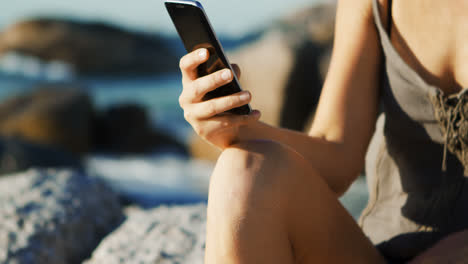 Female-volleyball-player-using-mobile-phone-in-the-beach-4k