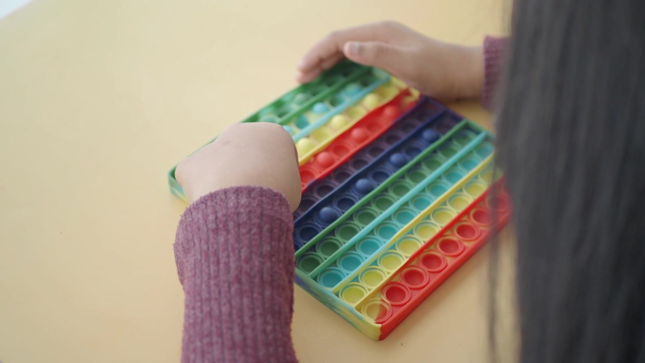 Bambino che Gioca con un Giocattolo Antistress Pop-it in Silicone Colorato