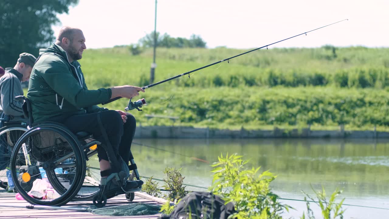 Pria penyandang disabilitas memancing di danau. Kursi roda. Berkemah. Musim panas.