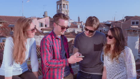 group of friends looking at a smartphone on a rooftop in venice