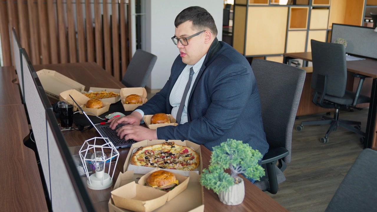 Overweight Businessman Working on Laptop Surrounded by Fast Food