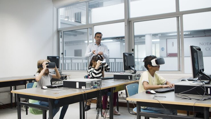 Tutor che osserva i bambini usare visori VR durante la lezione di informatica.