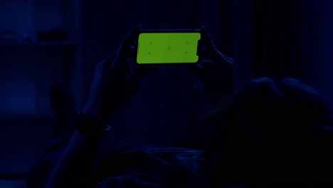 person lying down using a smartphone at night