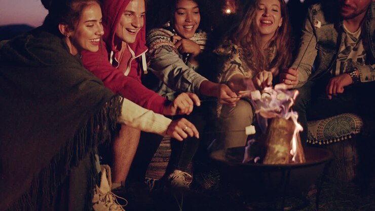 amigos disfrutando de los malvaviscos en la fogata.