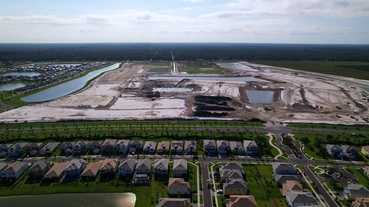 Aerial: West Palm Beach construction site with lakes during the day in Florida, USA, pull out drone shot