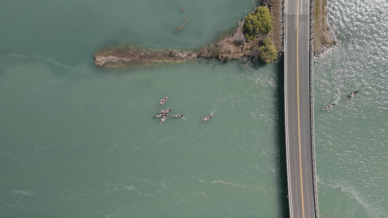 Aerial View of Canoes on a River with Bridge
