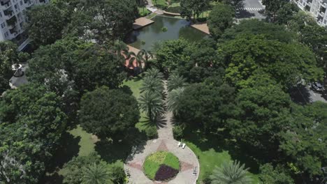 long wide aerial view of modern urban park featuring lakes, lush gardens, bridges, green space, pathways and trees