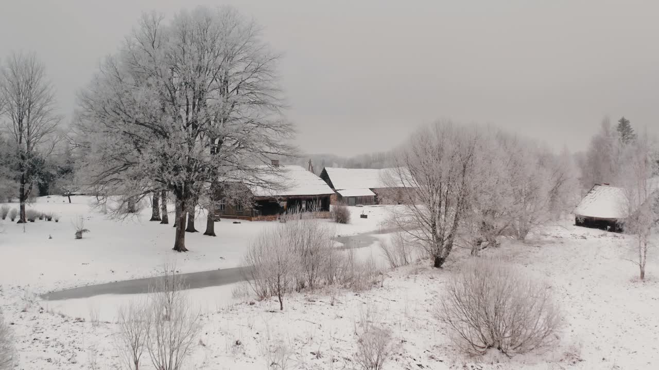 Flying towards ancient wooden family home with bath house and barn in the countryside. Breathtaking winter views with snow and frost on the trees.