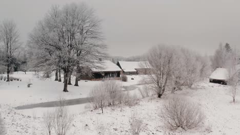 flying towards ancient wooden family home with bath house and barn in the countryside. breathtaking winter views with snow and frost on the trees.