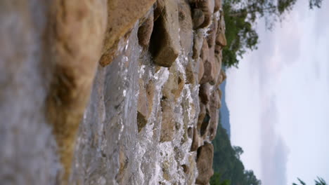 Vertical-of-a-clear-stream-running-through-stone-boulders-Abundant-river-flowing-in-slow-motion