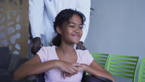 Mittelteil-Des-Arztes,-Der-Ein-Lächelndes-Afroamerikanisches-Mädchen-Im-Rollstuhl-Im-Krankenhaus-Schiebt