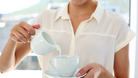 pretty businesswoman pouring milk into cup