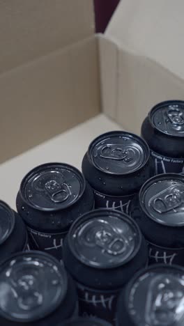 black beverage cans with condensation in a cardboard box