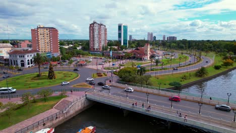 aerial dolly in of tigre river and argentinian flag waving in traffic circle while vehicles drive in it