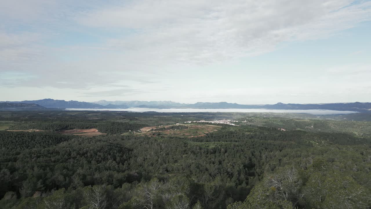 Montsant natural park in catalonia unveils a picturesque village nestled amidst lush greenery, partially obscured by a delicate layer of morning mist, creating a serene and captivating landscape