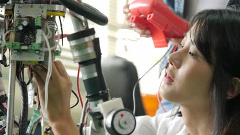 female electronics engineer building, testing, fixing robotics in laboratory. people with technology or innovation concept.