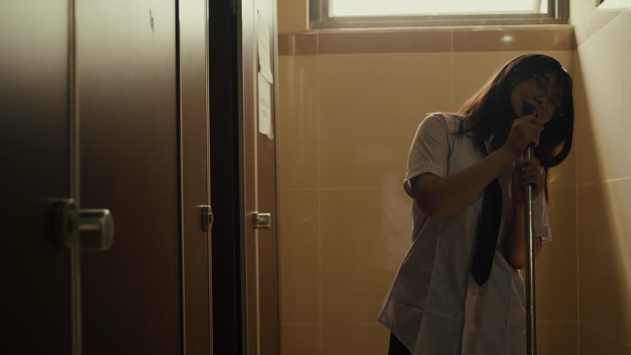 젊은 대학생은 혼자 춤을 추는 동안 학교 화장실의 바닥을 청소합니다.