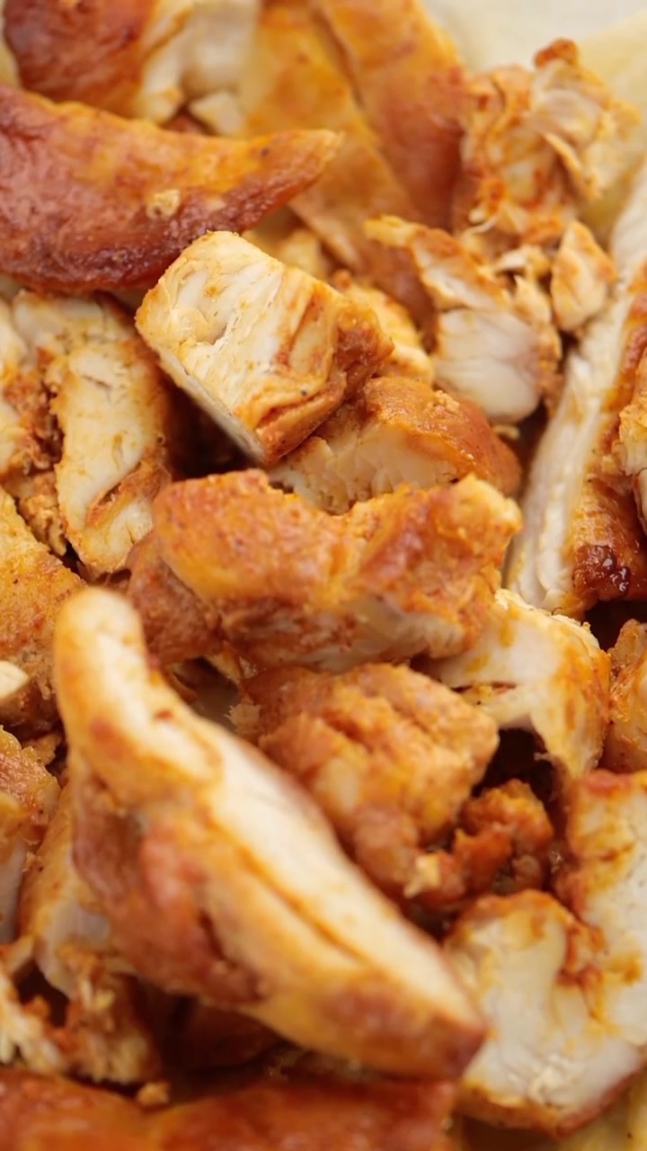 Primo piano di pezzi di pollo alla griglia conditi che vengono messi in una ciotola