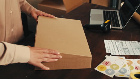 e-commerce storage shop, woman packing goods and clothes for second hand delivery market, dedicated packaging and shipping workspace with supplies and technology for efficiency, online sales.
