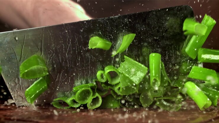 Fresh Green Onions Chopped in Slow Motion on a Cutting Board