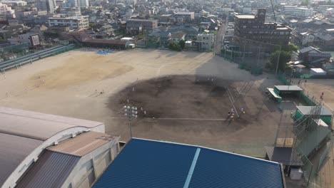 aerial drone fly above sports stadiums, dirt baseball fields, school in fukui prefecture, japan during a sunny day