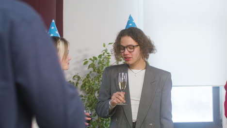 happy boy and girl with party hat drinking and talking together at the office party 1