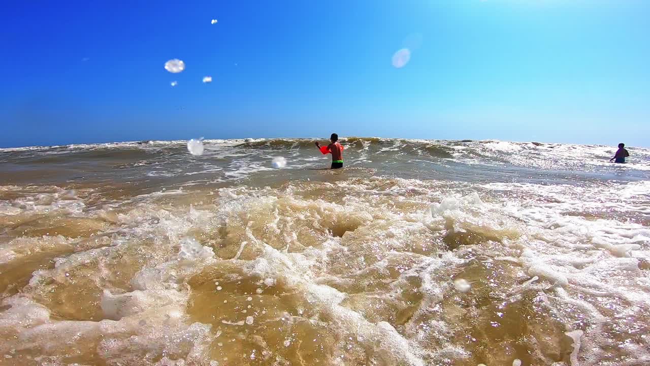 Boy Jumping In Sea Waves. Happy boy running and jumping at shallow water