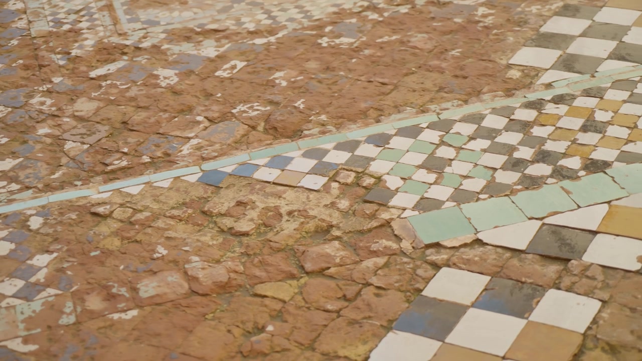 Worn mosaic tile floor with geometric patterns in historic Marrakesh setting