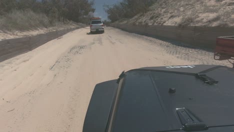jeep negro conduce por una pista arenosa siguiendo a otro vehículo 4x4 a través del monte
