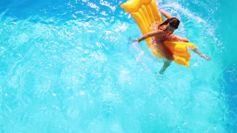 Overhead-of-brunette-sitting-on-lilo-in-pool-on-sunny-day