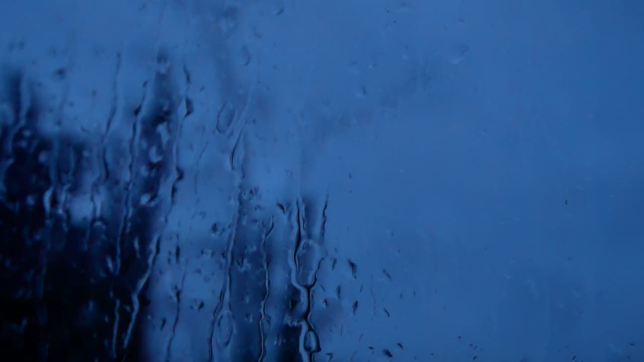 gotas de tormenta lluviosa en la noche, mal humor caen por el cristal de la ventana closeup bokeh