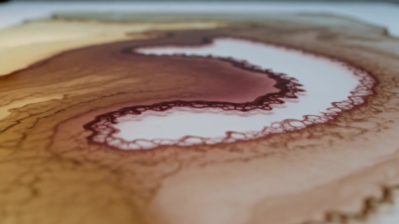 Pigmento marrone che si diffonde creando una banda a S sinuosa su carta bianca dopo il contatto con l'acqua, vista macro