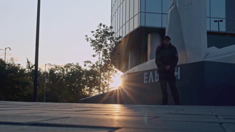 man standing in front of a modern building at sunset