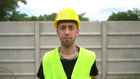 industrial worker in reflectorized vest knocks on yellow hard hat with hand