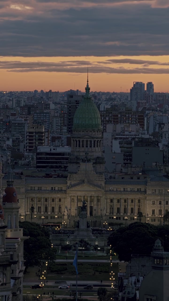 Panoramica aerea verticale verso destra sul Congresso Nazionale Argentino e la sua cupola verde durante il tramonto nel centro di Buenos Aires.