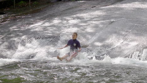 slow motion of boy going down sliding rock in north carolina