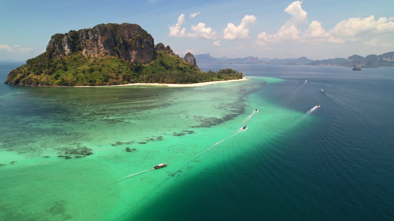 Ripresa aerea ad alta quota di molte barche longtail thailandesi che portano turisti in un tour dell'isola intorno alle splendide barriere coralline dell'isola di Ko Poda a Krabi, Thailandia, in una soleggiata giornata estiva nel Mare delle Andamane