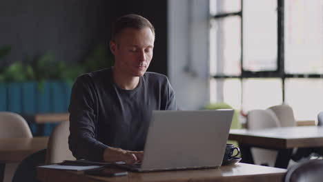 hermoso desarrollador masculino o estudiante trabajando estudiando con computadora portátil en una cafetería. trabajo remoto independiente educación en línea autónomo