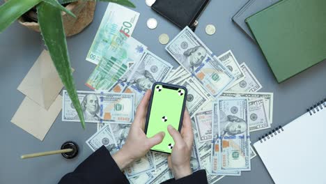 making money online. internet investments. businesswoman using mobile app for investing. online casino winning, winning on financial stock market. smartphone with green screen and money on table.